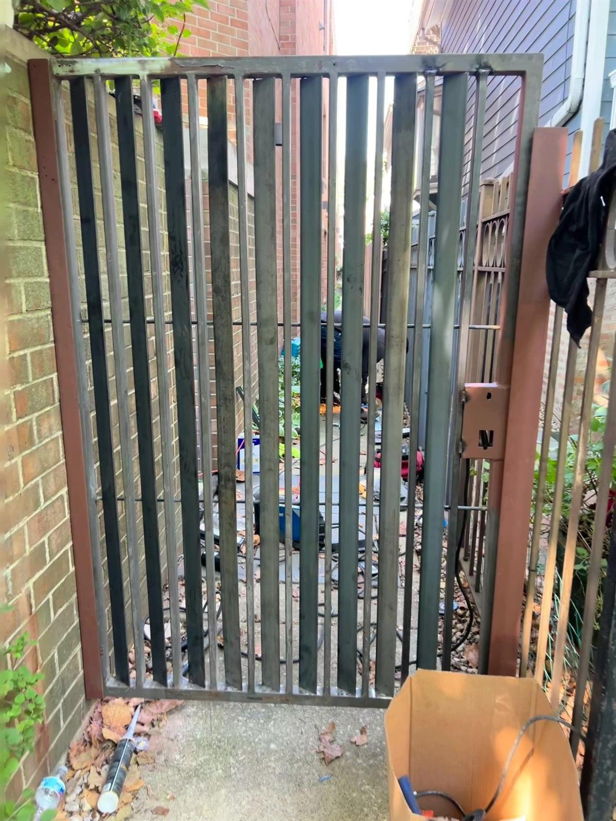 Custom steel gate being fabricated and fitted on site, welds still raw