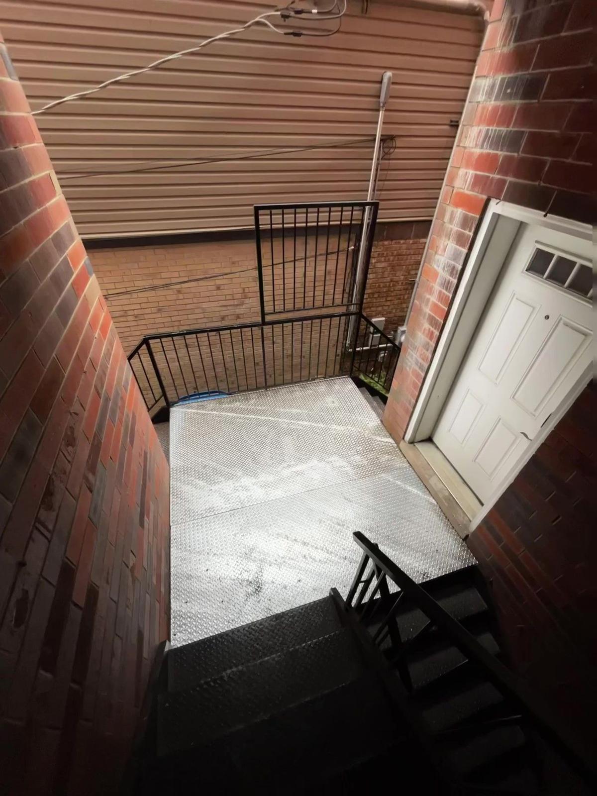 Custom diamond-plate landing and steel gate fabricated between brick buildings