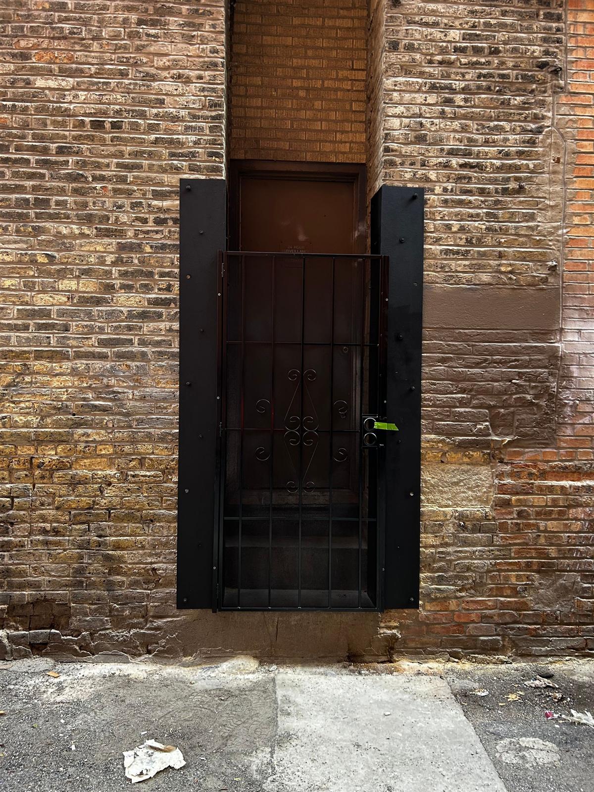 Black steel security gate and panels protecting an alley entry door
