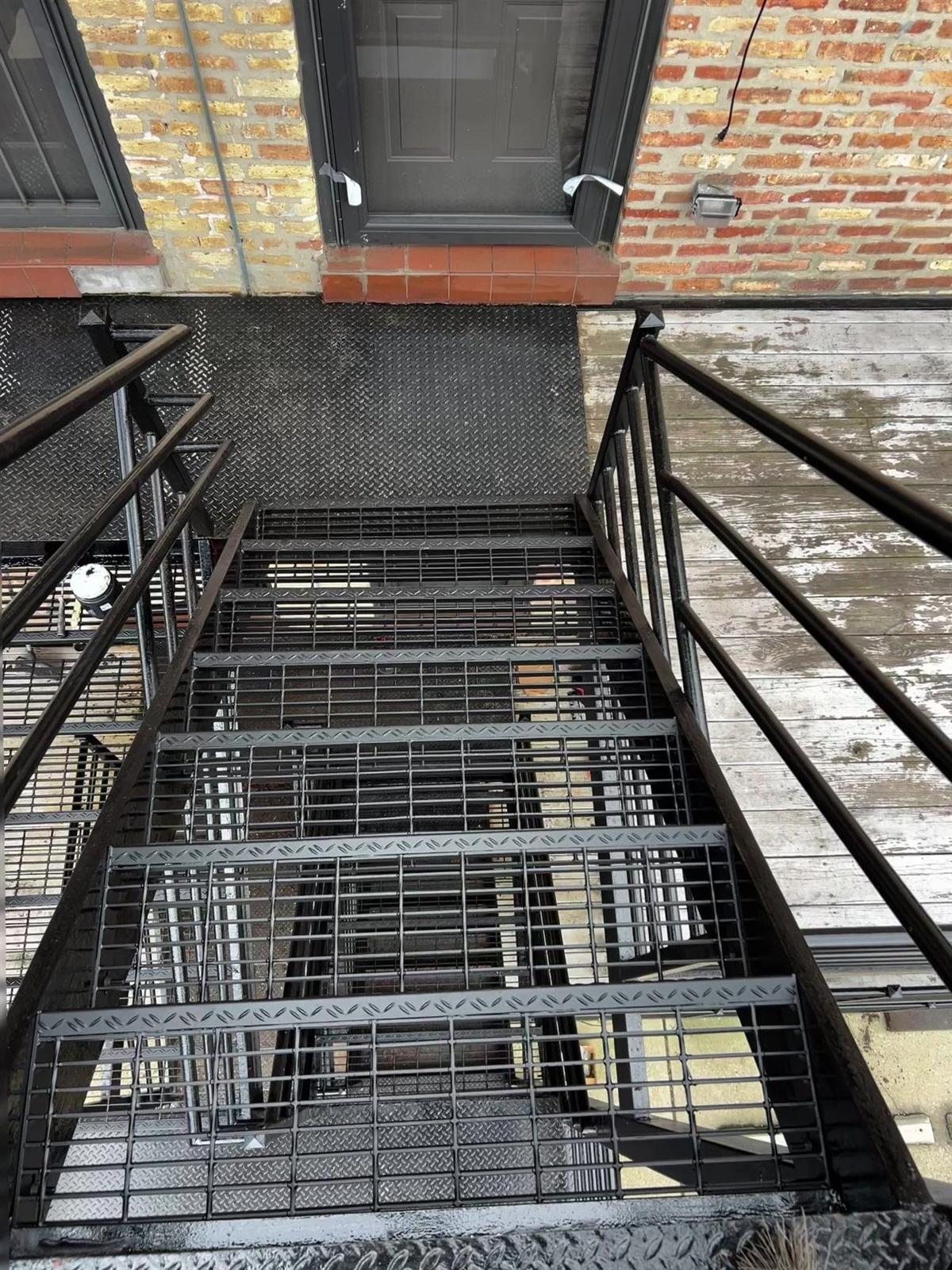 New steel stairs with bar-grating treads and diamond-plate landing on a back porch