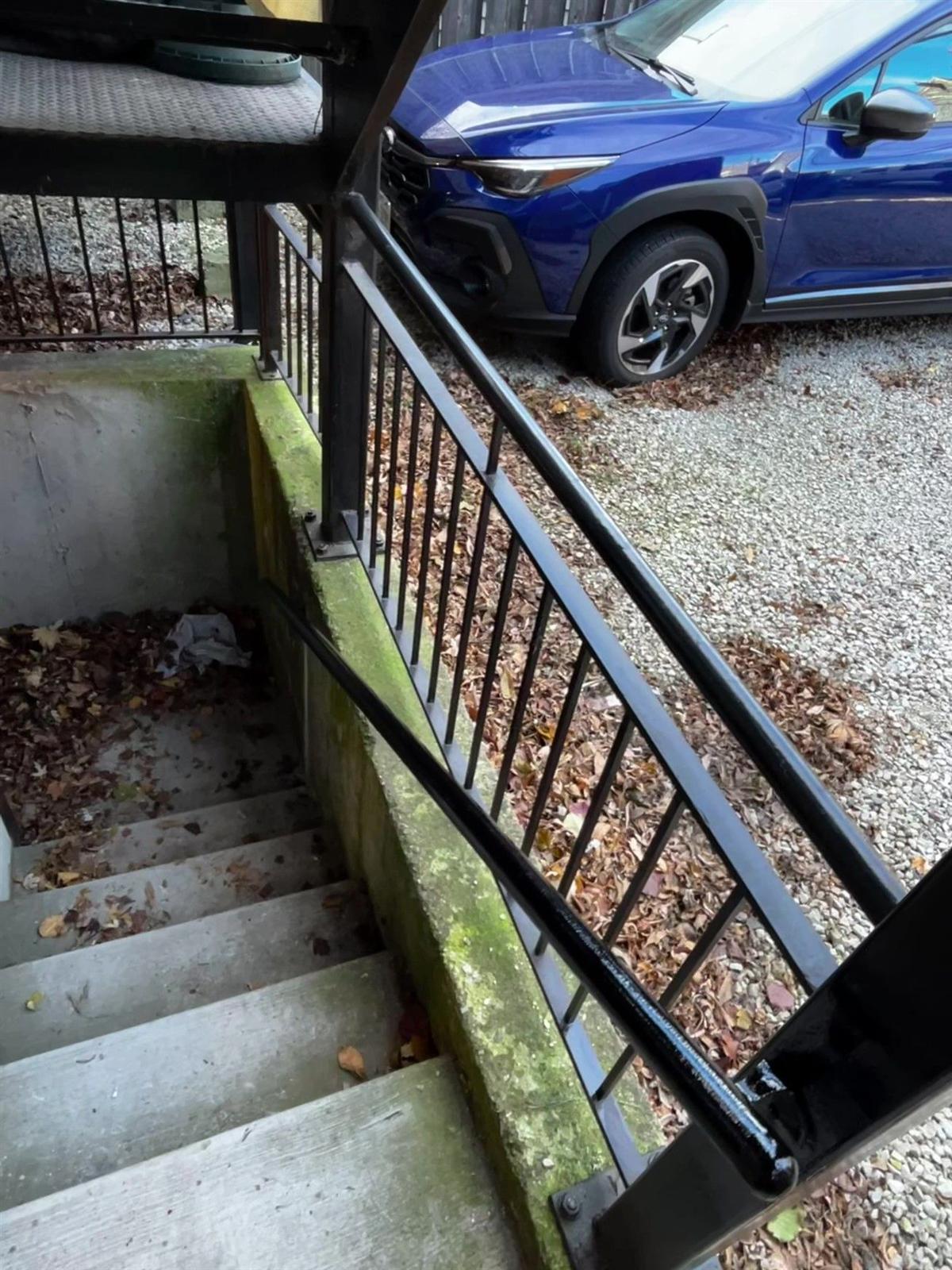 Black steel railing and handrail installed at exterior basement stairs