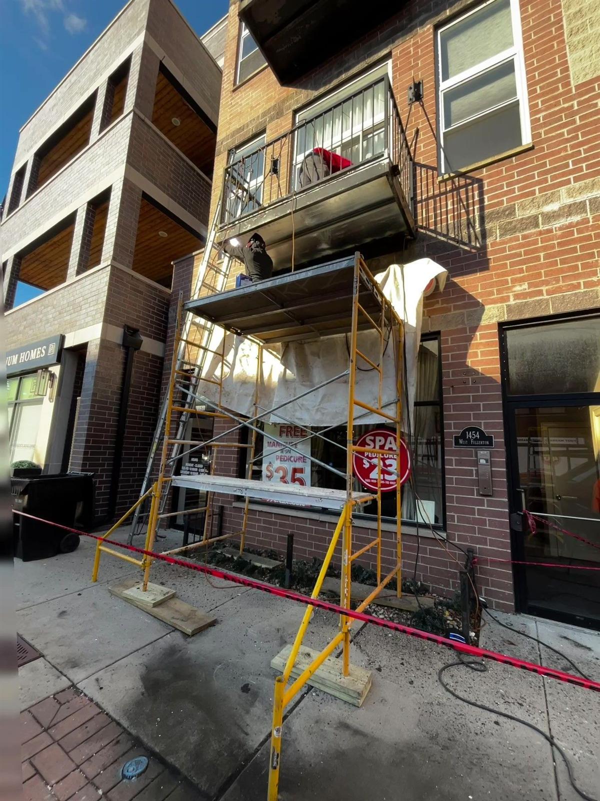 Midwest Welders crew performing on-site balcony repair from scaffolding on a Chicago street